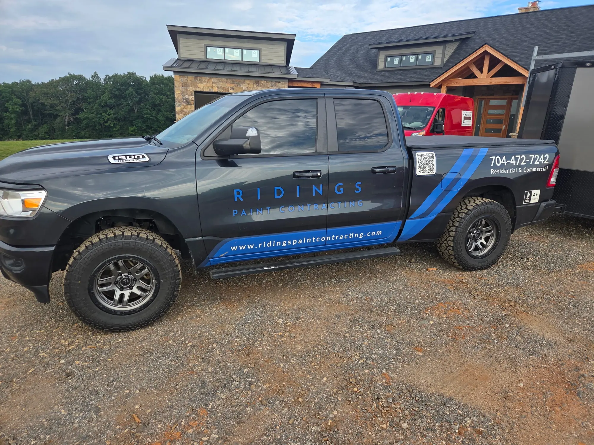 Dark gray pickup truck with blue company lettering and sweeping blue stripes along the doors and bed
