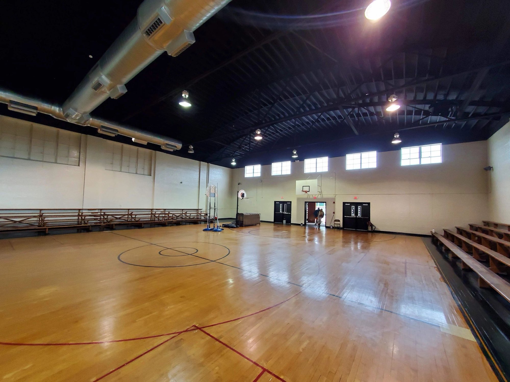 School gymnasium after painting, with white walls and a black ceiling