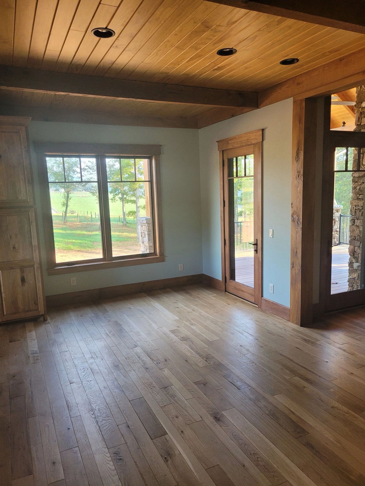 Room with light blue walls, a stained wood ceiling and wood window trim