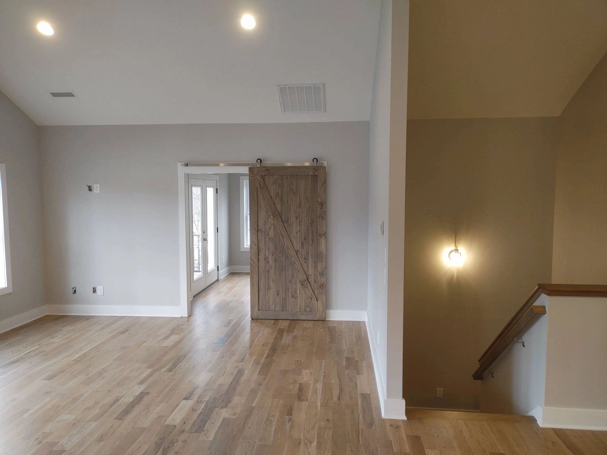 Open room with light gray walls, white trim and a sliding barn door