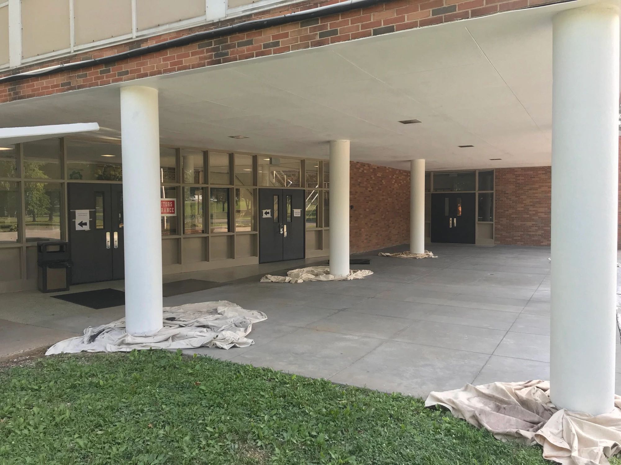 School entrance with freshly painted white columns and drop cloths on the walkway