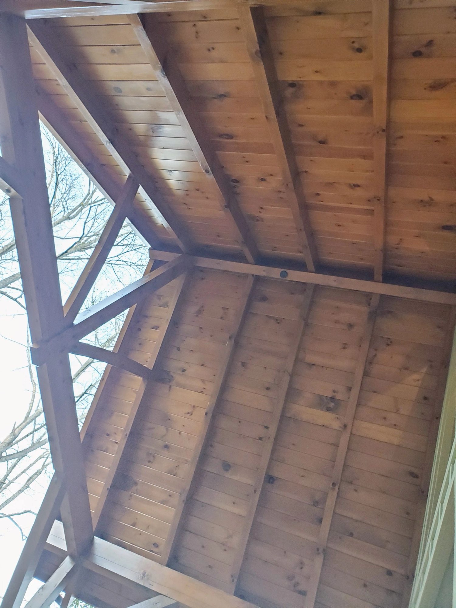 Stained tongue-and-groove porch ceiling with exposed timber trusses